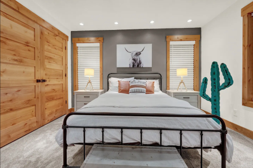 Cozy bedroom with a large bed, wooden accents, and a cactus decoration, featuring a bull artwork on the wall.